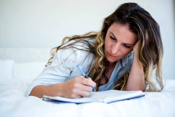 istock woman lying in her bed writing in a book 851803516