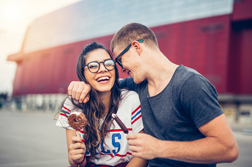 19 years old couple enjoy outdoors. They are eating ice cream after shopping