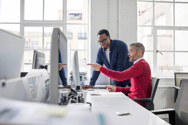 Businessman pointing at computer to colleague