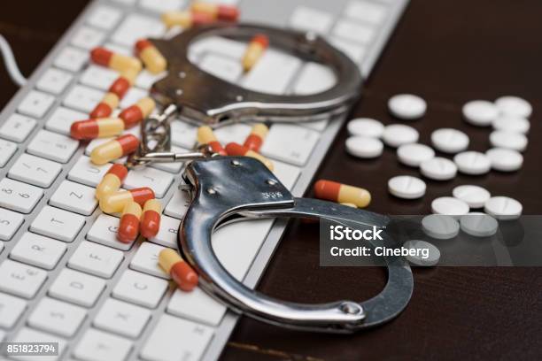 Handcuffs And Pills Over Computer Keyboard Stock Photo - Download Image Now - Stealing - Crime, Healthcare And Medicine, Law