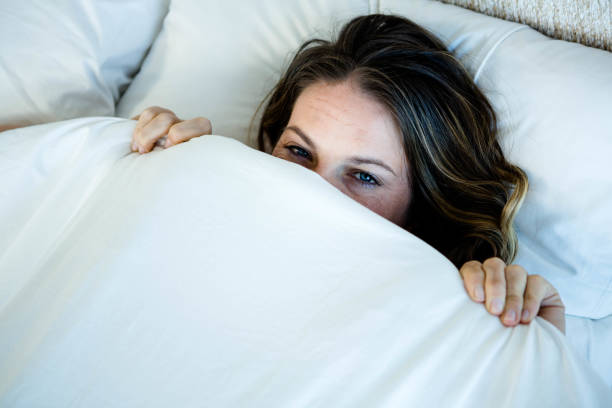 istock smiling woman hiding behind her duvet 851824098
