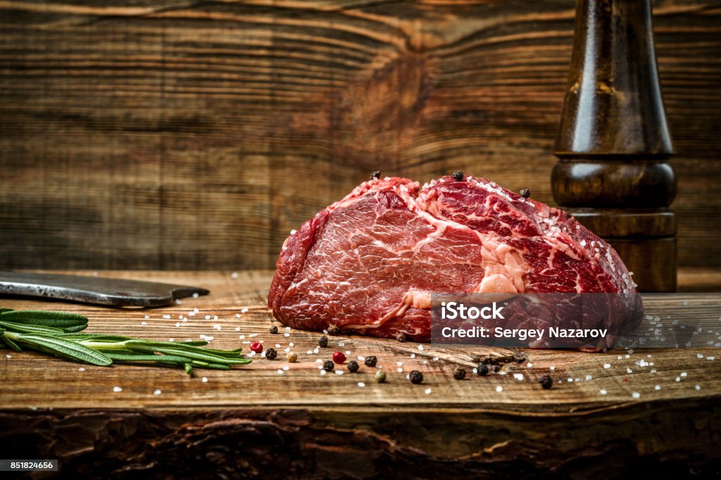 Bistecca ribeye stagionata secca con condimento su sfondo di legno - Foto stock royalty-free di Carne