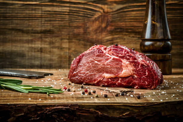 dry aged ribeye steak with seasoning on wooden background - carne talho imagens e fotografias de stock