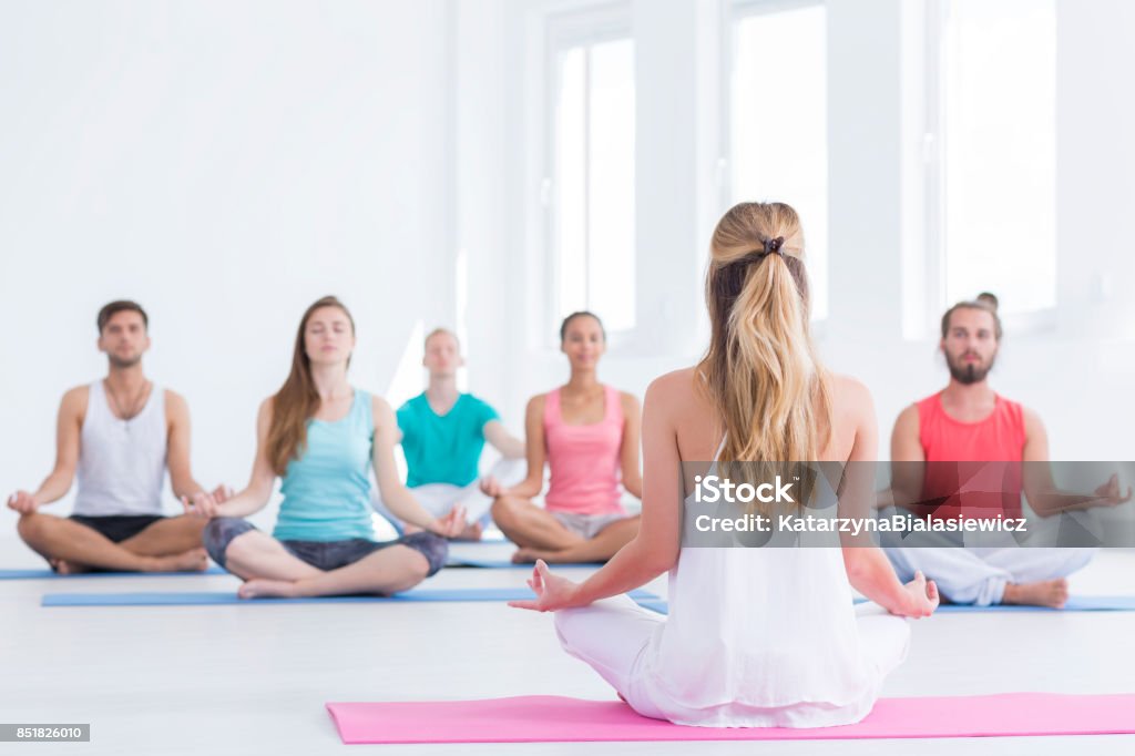 Yoga instructor in studio Yoga instructor is showing lotus position in white studio Yoga Class Stock Photo
