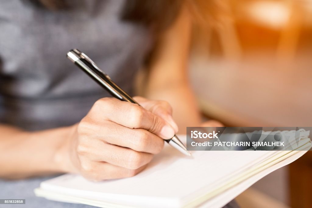 Women holding a pens writing a notebook. Recording concept Writing - Activity Stock Photo