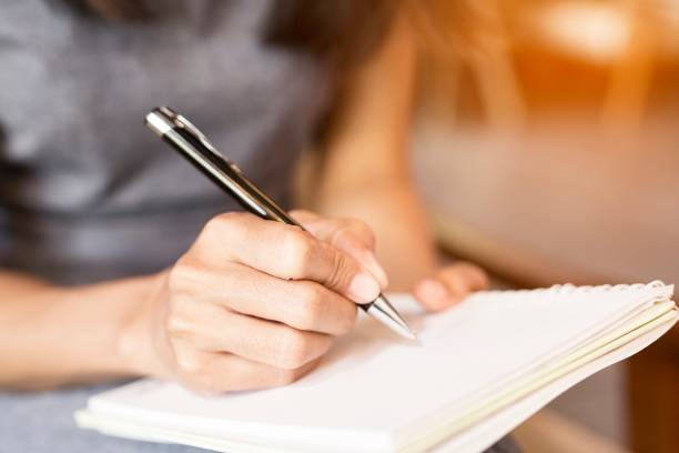 у женщин, держащих ручки, пишут тетрадь. концепция записи - notebook book paper note pad стоковые фото и изображения