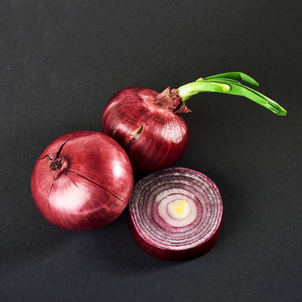 istock Red onions whole, isolated on a black background 851846528