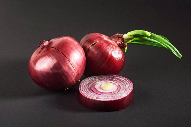 istock Red onions whole, isolated on a black background 851846582