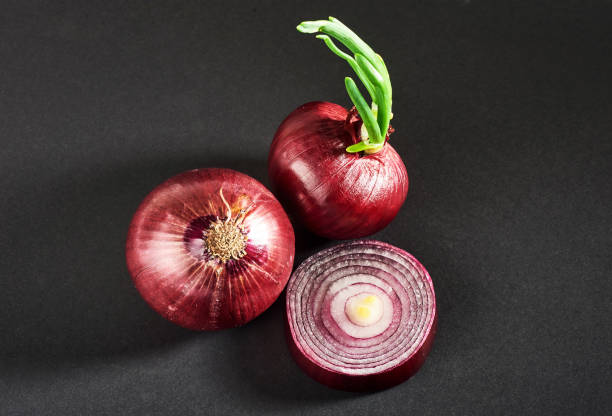 istock Red onions whole, isolated on a black background 851846716