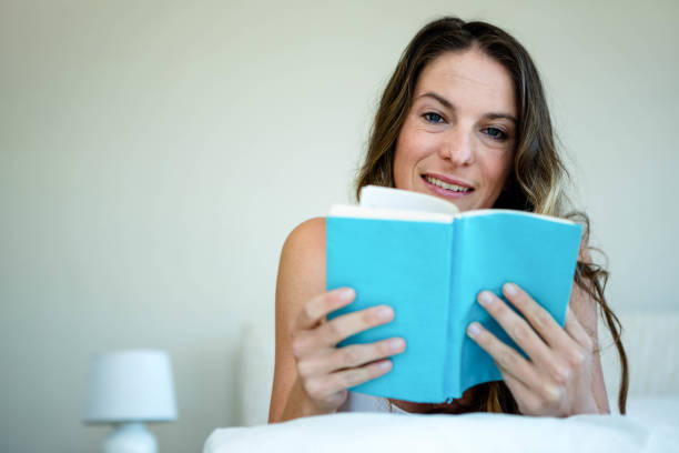 istock smiling woman in bed reading a book 851847186