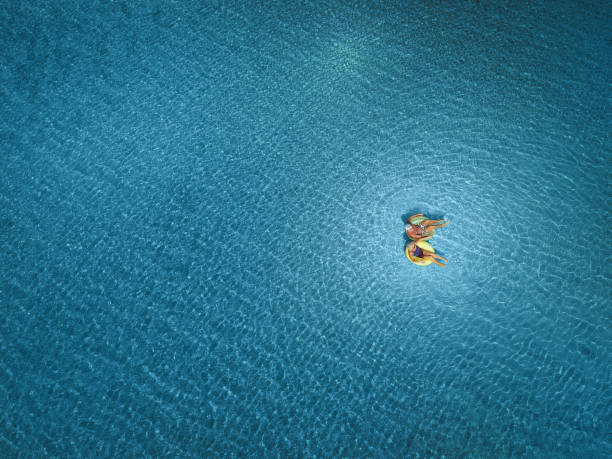 High angle view photo of a senior couple floating in the ocean while using swimming and floating devices