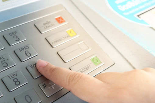 Asian woman hand presses code at cash machine(ATM). The security code must be entered and the cash card must be used. copy space. business concept.