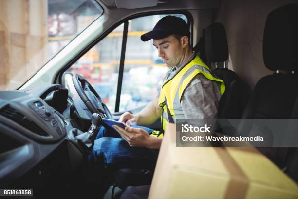 Delivery Driver Using Tablet In Van With Parcels On Seat Stock Photo - Download Image Now