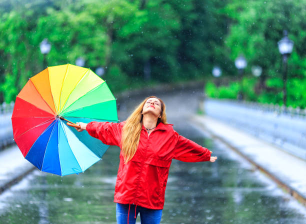 istock Happy young woman walking with umbrella under the rain 851870634