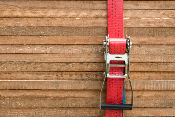 red ratchet strap fixing wood boards / wooden planks red ratchet strap fixing wood boards / wooden planks  / stacked tables tineola stock pictures, royalty-free photos & images