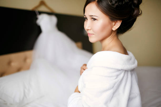 A bride in a white robe from the morning before putting on a wedding dress on a wedding day stock photo