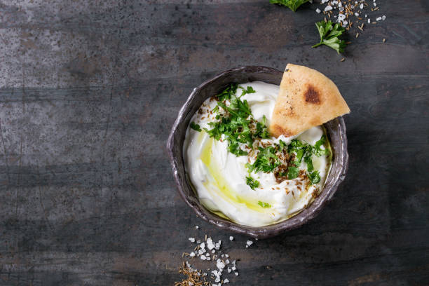 labneh fresh lebanese cream cheese dip labneh middle eastern lebanese cream cheese dip with olive oil, salt, herbs served traditional pita bread in terracotta bowl over dark texture metal background. Top view with space greek yogurt photos stock pictures, royalty-free photos & images