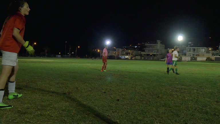 Young female soccer players playing on field at night