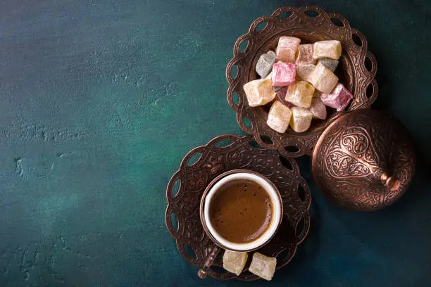 Photo of Traditional turkish coffee  and turkish delight on dark green wooden background. flat lay