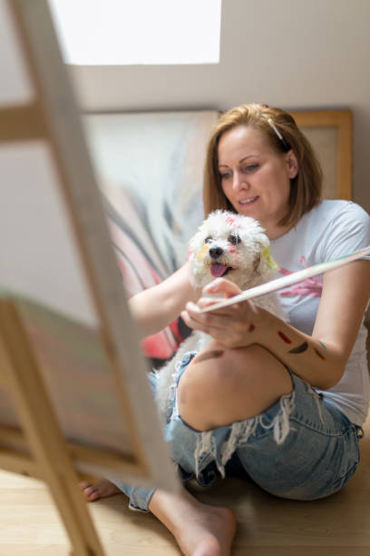 istock Happy young woman paints on canvas 851886416