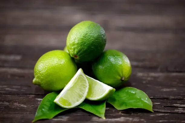 Photo of lime juice with lime slices on wooden table