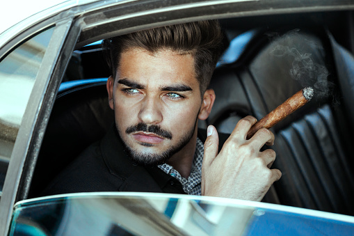 Pensive businessman in a limousine smoking cigar looking through window