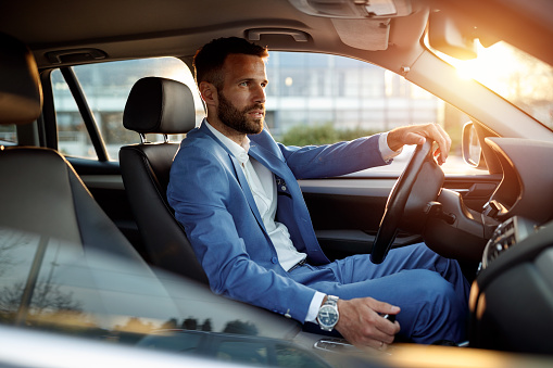 Attractive elegant man in business suit driving car