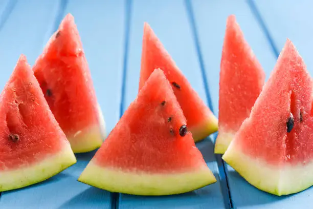 Fresh watermelon slices on blue background look like sails in blue sea