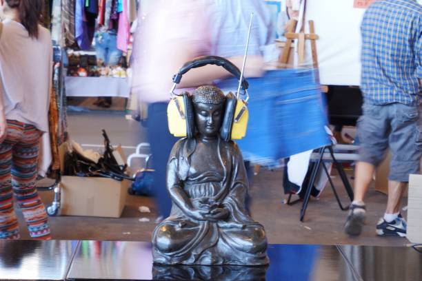 Meditating buddha statue wearing headphones, people passing by