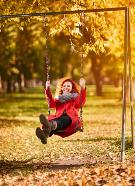 istock Happy redhead woman on swing in park 851900140
