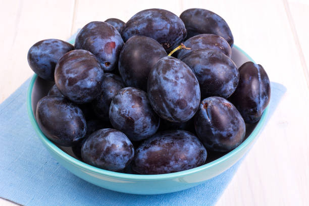 istock Blue ceramic bowl with plums on white wooden background 851900794