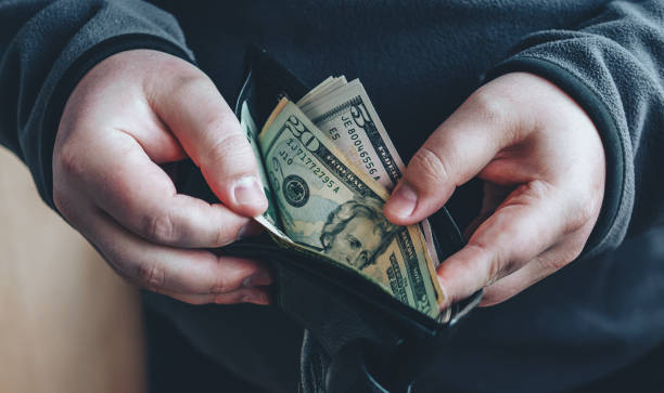 istock Hands holding us dollar bills and open wallet or pouch.  Man counting money 851903534
