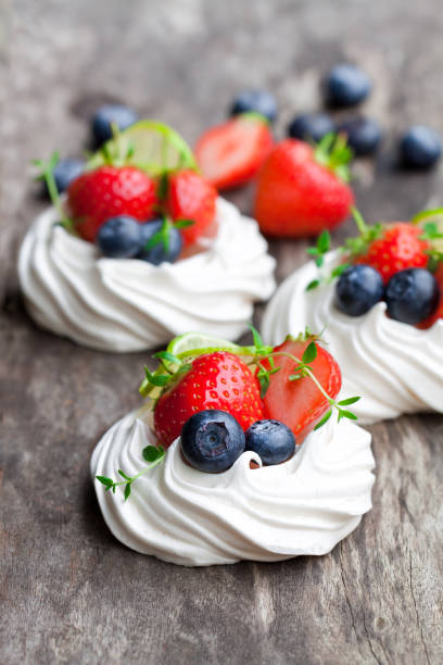 istock Mini  Pavlova meringue cakes with berries and lime on rustic wooden background 851904718