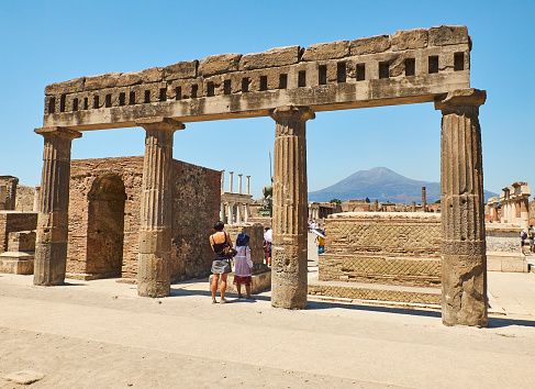 Pompei, Italy - August 9, 2017. Tourists in Colonnade of Popidius of the Civil Forum at Ruins of Pompeii. The city was an ancient Roman city destroyed by the volcano Vesuvius. Pompei, Campania, Italy.