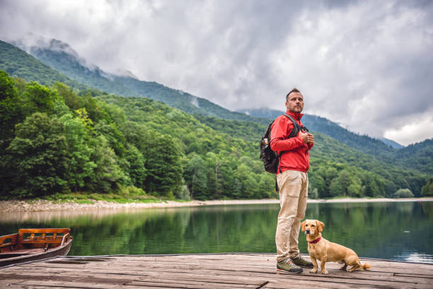istock Men with a dog standing on pier by the lake 851919564