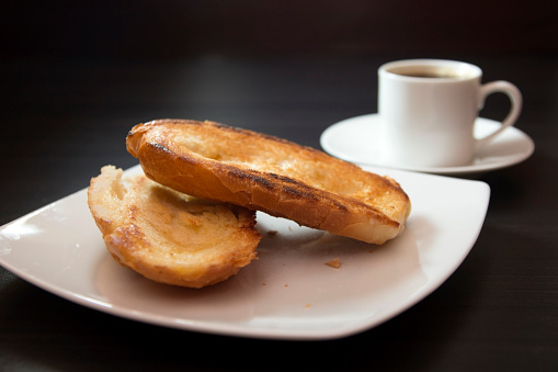 French bread toasted with butter on the plate with coffee. Pao na chapa traditional brazilian breakfast. Selective focus.