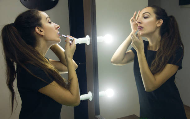 istock Woman Apply Lipstick Looking Into Mirror 851920038