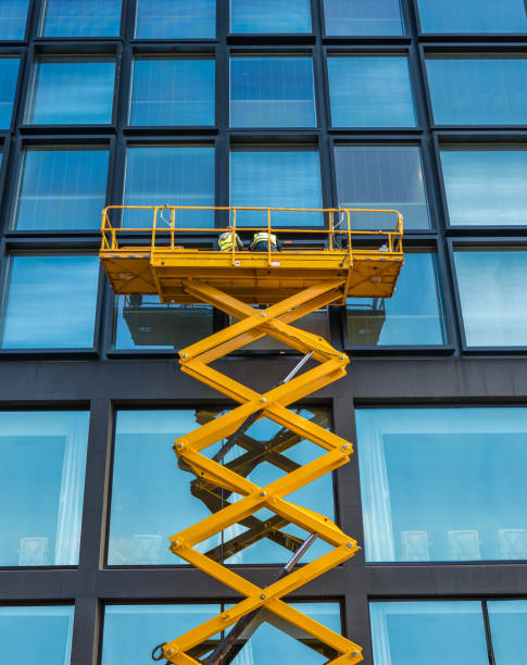 Scissor Lift Office Block Workers On A Scissor Lift Cleaning Windows On A Financial Building Downtown hoisting photos stock pictures, royalty-free photos & images