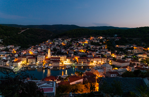 Pucisca, Croatia, Dalmatia - small romantic Croatian town located on the island of Brac, at the bay. Evening summer landscape with colorful lights and water reflections. Travel destination.