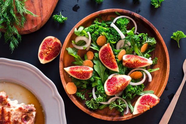 istock Autumn salad of arugula, figs in a brown earthenware plate on a dark background. top view 851928072
