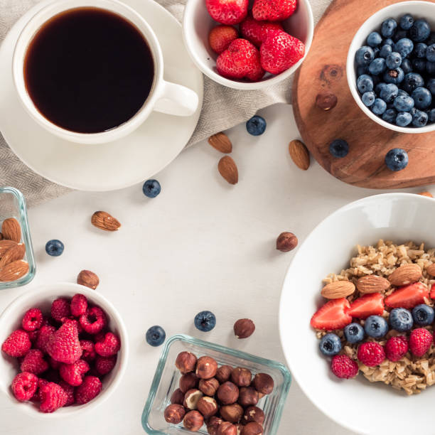 Good morning - healthy breakfast background with oatmeal coffee, berries, egg, nuts. White wooden food background, top view