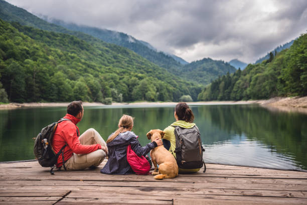 Family with dog resting on a pier Family with a small yellow dog resting on a pier and looking at lake and foggy mountains serbia photos stock pictures, royalty-free photos & images