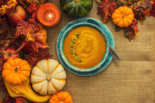 Butternut squash soup decorated with fresh pumpkins and maple leaves