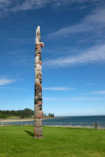 Skidegate forest totem pole Haida Gwaii British Columbia Canada In the town of Skidegate, a colorful totem pole faces Rooney Bay and Skidegate Inlet on Haida Gwaii or Queen Charlotte Islands, British Columbia, Canada. haida gwaii totem poles stock pictures, royalty-free photos & images