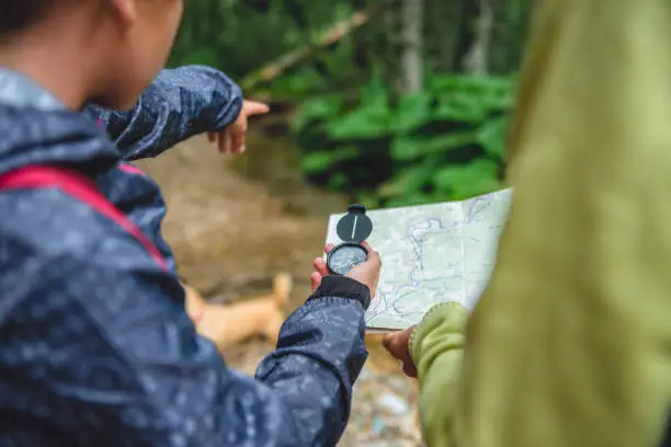 Photo of Daughter and mother hiking in forest and using compass
