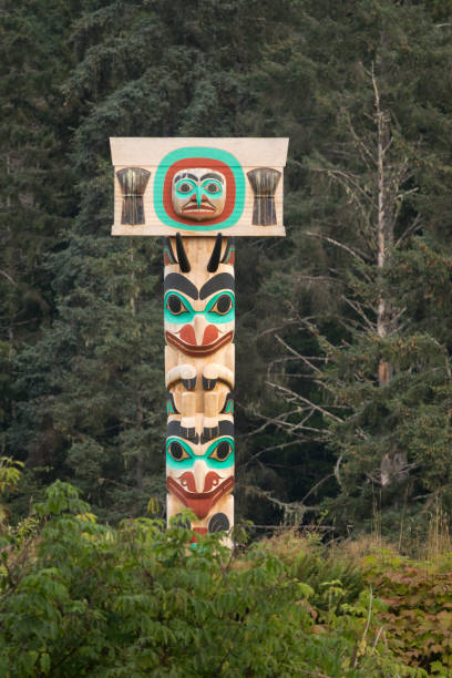 Skidegate forest totem pole Haida Gwaii British Columbia Canada In the town of Skidegate, a colorful totem pole faces Rooney Bay and Skidegate Inlet on Haida Gwaii or Queen Charlotte Islands, British Columbia, Canada. haida gwaii totem poles stock pictures, royalty-free photos & images