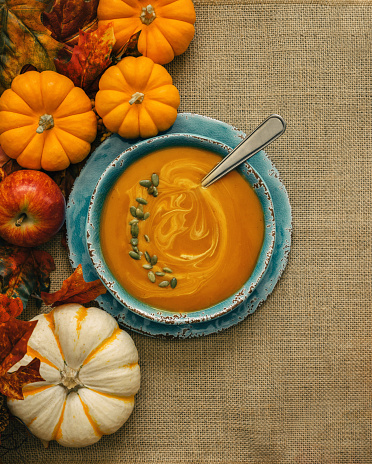 Butternut squash soup decorated with fresh pumpkins and maple leaves
