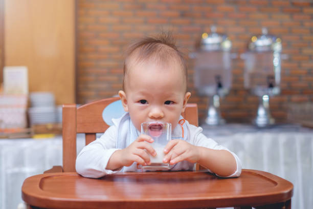 carino piccolo asiatico 18 mesi / bambino di 1 anno bambino che beve latte in un bicchiere - buffet thai cuisine asian ethnicity food foto e immagini stock