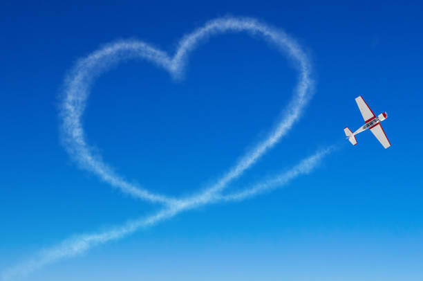 любовь образное сердце от белого дыма след самолета - skywriting стоковые фото и изображения