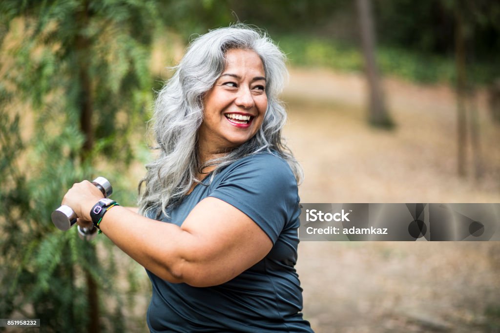 Senior Mexican Woman Working Out A beautiful senior Mexican Woman working out and stretching with weights Exercising Stock Photo